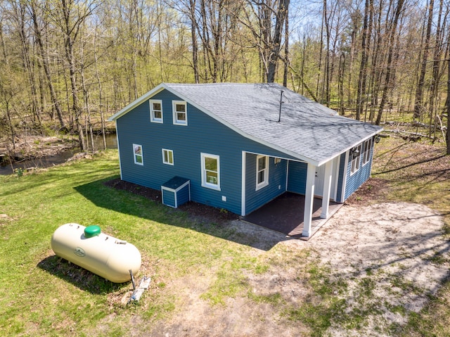 view of side of home featuring a shingled roof and a yard