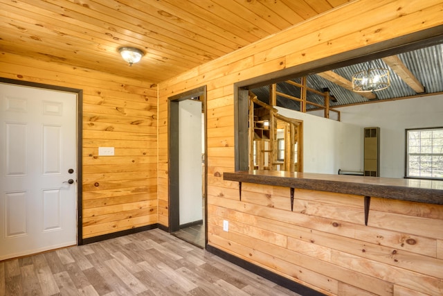 foyer entrance featuring wood walls, wood finished floors, wood ceiling, and baseboards
