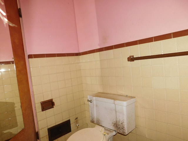 bathroom with tile walls and toilet