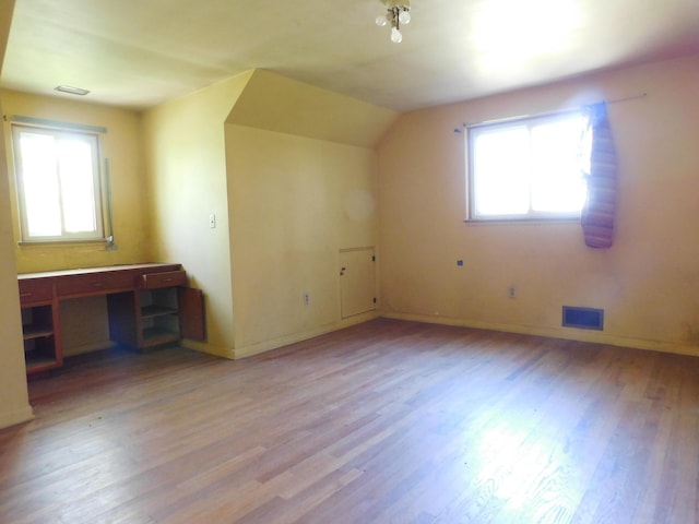 additional living space with wood finished floors, baseboards, and vaulted ceiling
