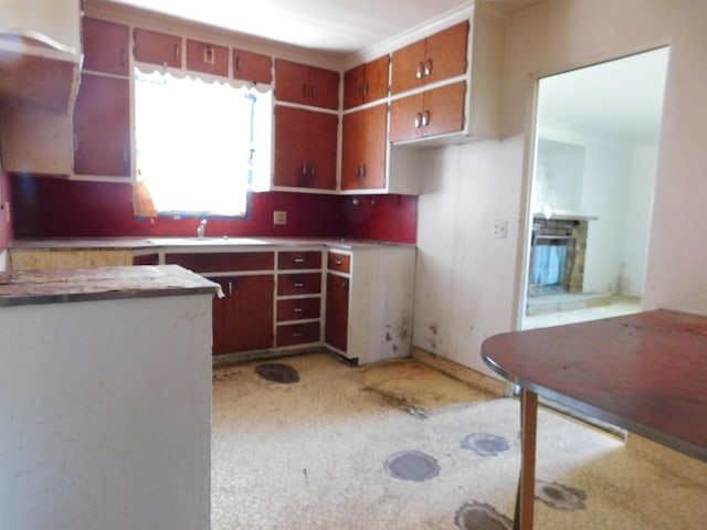 kitchen featuring a sink, light colored carpet, brown cabinets, and light countertops