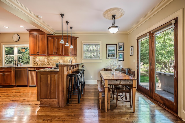 dining space featuring dark wood-type flooring, ornamental molding, and baseboards