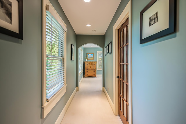 hall with arched walkways, light carpet, recessed lighting, and baseboards