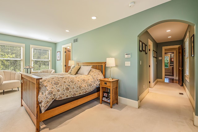 carpeted bedroom with arched walkways, baseboards, and recessed lighting