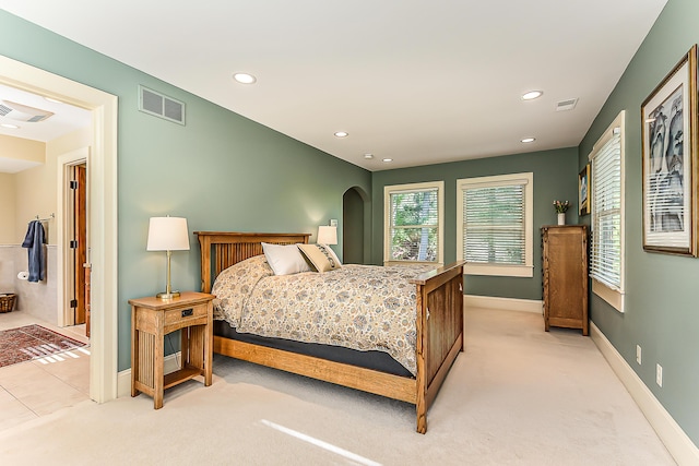 bedroom with light carpet, recessed lighting, baseboards, and arched walkways