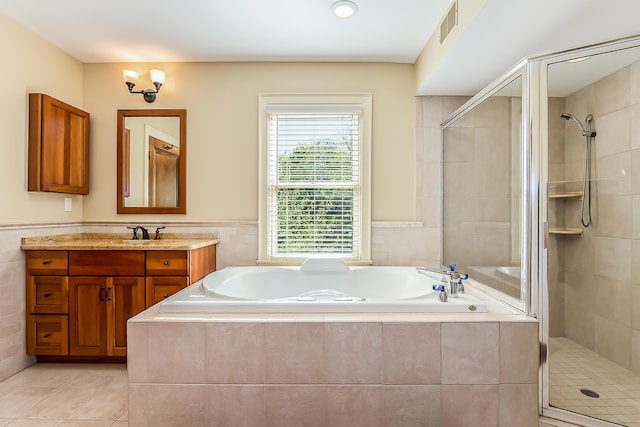 bathroom featuring a shower stall, tile patterned floors, a bath, vanity, and wainscoting