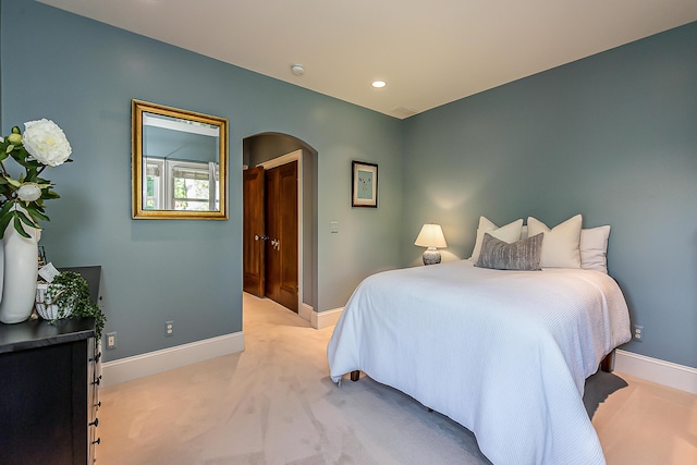 bedroom with arched walkways, baseboards, light carpet, and recessed lighting