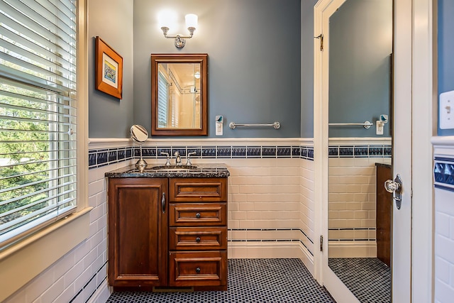 bathroom featuring tile walls, plenty of natural light, wainscoting, tile patterned flooring, and vanity