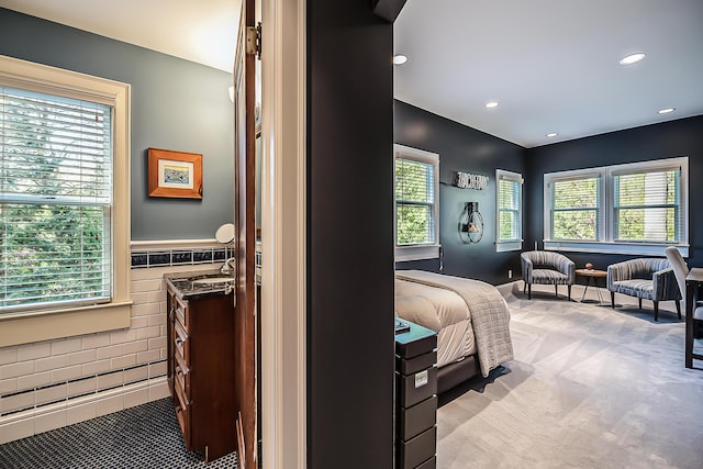 bedroom featuring tile walls, recessed lighting, wainscoting, and light colored carpet