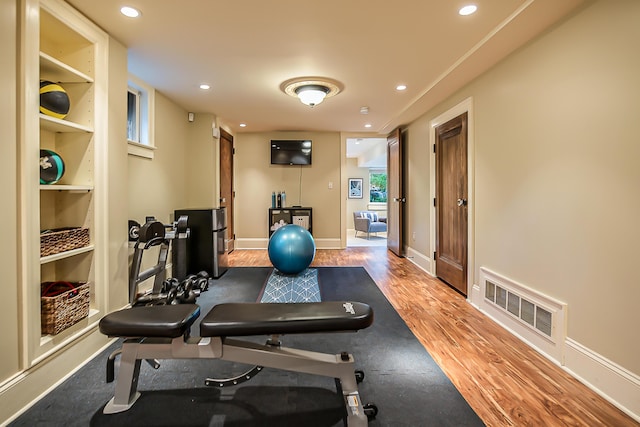 exercise room featuring wood finished floors, recessed lighting, and baseboards