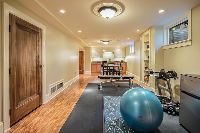 workout area featuring light wood-style floors, baseboards, and recessed lighting