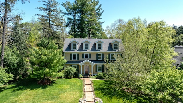 view of front facade featuring a front lawn and view of wooded area