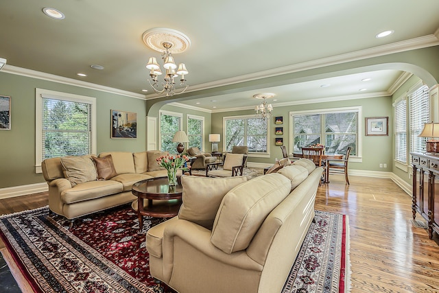 living room featuring arched walkways, a chandelier, wood finished floors, baseboards, and crown molding