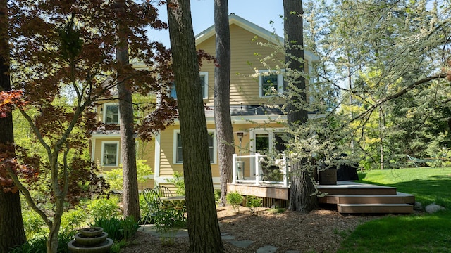 back of property with a wooden deck and a lawn