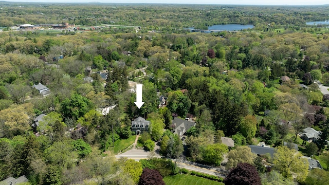 aerial view of property and surrounding area featuring a heavily wooded area and a nearby body of water