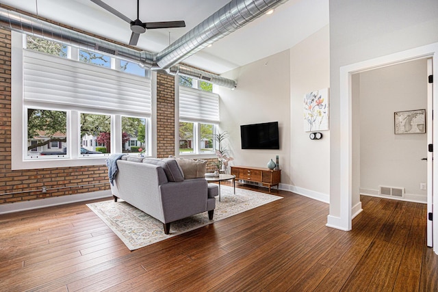 2214 S State St Unit 108, Saint Joseph, MI 49085 - living room featuring a high ceiling, a ceiling fan, hardwood / wood-style floors, baseboards, and brick wall