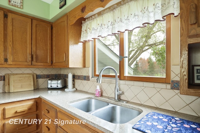 919 E Salzburg Rd, Bay City, MI 48706 - kitchen featuring a sink, brown cabinetry, decorative backsplash, and light stone countertops