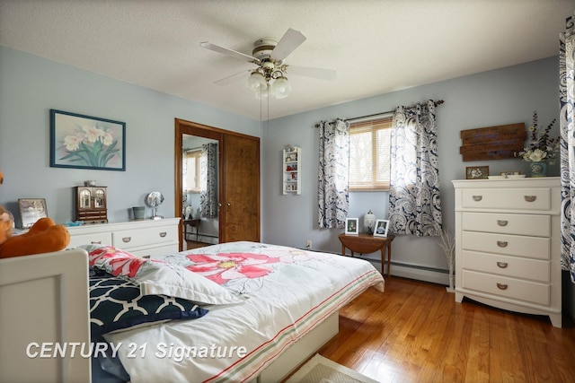 919 E Salzburg Rd, Bay City, MI 48706 - bedroom featuring a baseboard heating unit, wood finished floors, a ceiling fan, and a closet