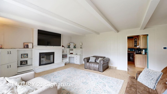 living room featuring beamed ceiling and a glass covered fireplace