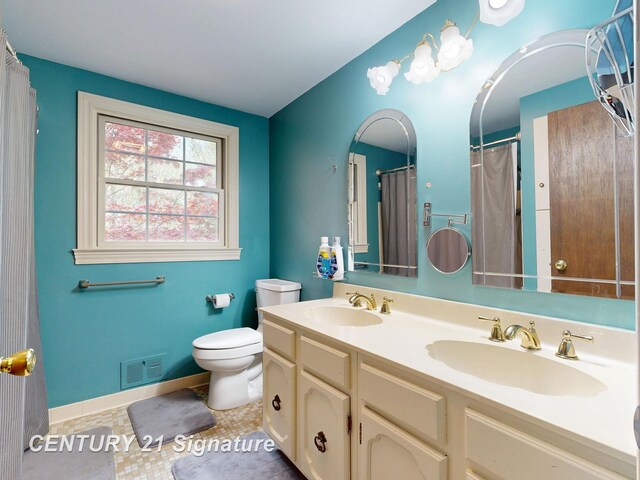 full bathroom with toilet, double vanity, and baseboards