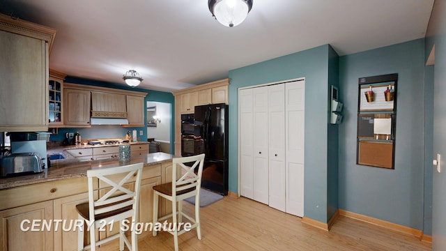 kitchen with a peninsula, glass insert cabinets, light wood-type flooring, baseboards, and a kitchen breakfast bar