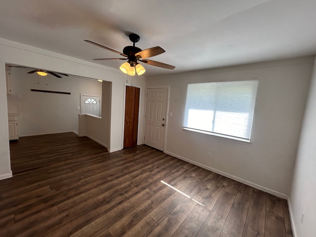 empty room with ceiling fan, baseboards, and dark wood-style floors