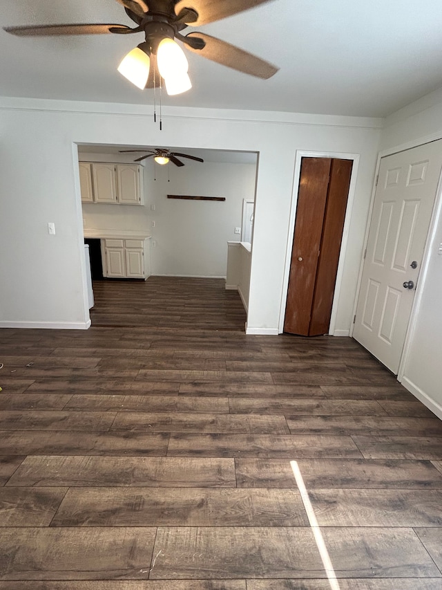 unfurnished living room with ceiling fan, dark wood-type flooring, and baseboards