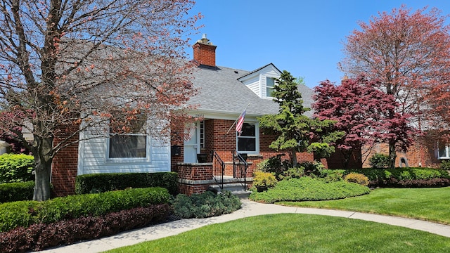 28051 Garfield St, Roseville, MI 48066 - cape cod-style house featuring a chimney, a front yard, a shingled roof, and brick siding
