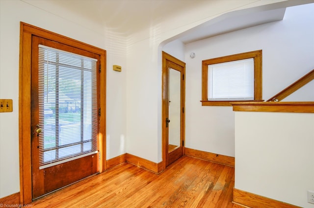 entryway featuring light wood-style floors, baseboards, and arched walkways