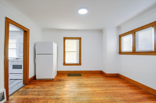 empty room featuring plenty of natural light, light wood finished floors, and baseboards