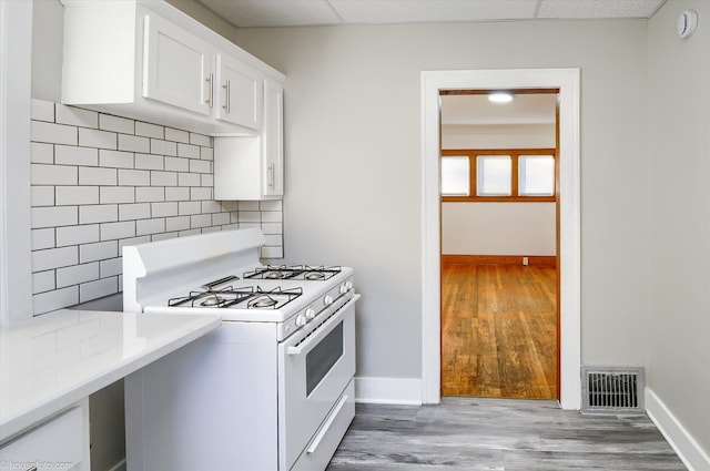 kitchen with white gas range, baseboards, wood finished floors, and white cabinets