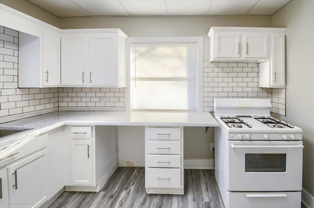 kitchen with white range with gas stovetop, light wood-type flooring, white cabinets, light countertops, and a drop ceiling