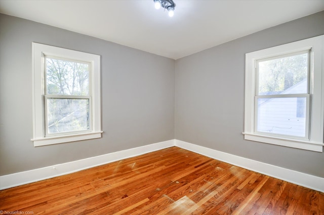 spare room with baseboards and wood finished floors