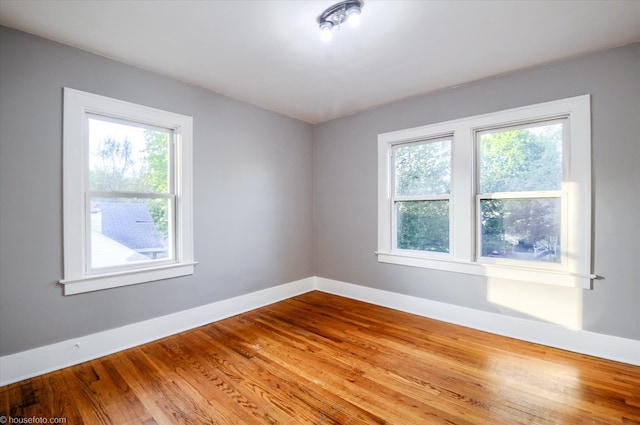 empty room with plenty of natural light, baseboards, and wood finished floors