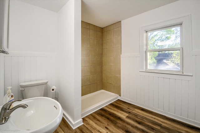 full bathroom featuring wainscoting, a sink, wood finished floors, a shower stall, and toilet