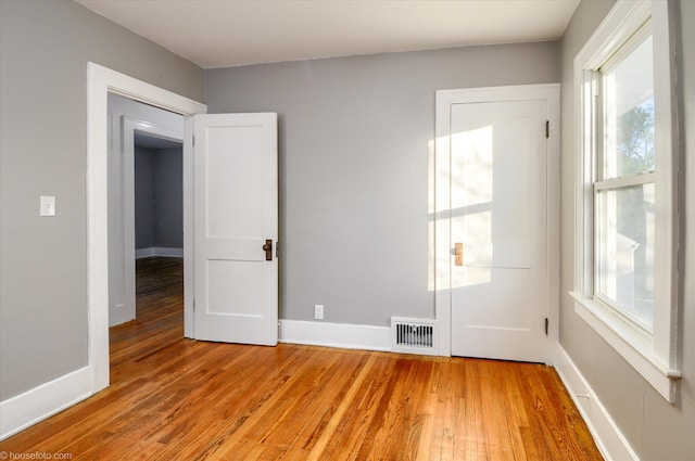 empty room with light wood finished floors, plenty of natural light, and baseboards