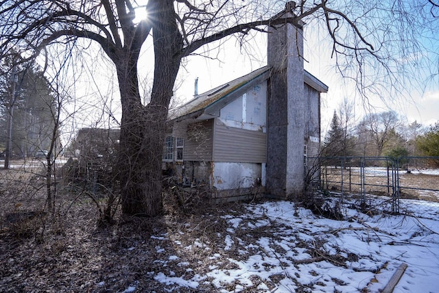3110 Sigma Rd, Kalkaska, MI 49646 - view of snow covered exterior featuring a chimney and fence