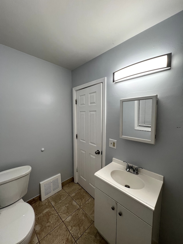 half bath featuring toilet, tile patterned flooring, and vanity