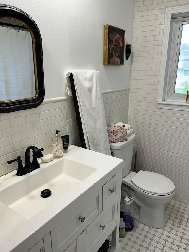 14074 Barbara St, Livonia, MI 48154 - bathroom featuring tile walls, vanity, toilet, a wainscoted wall, and tile patterned floors