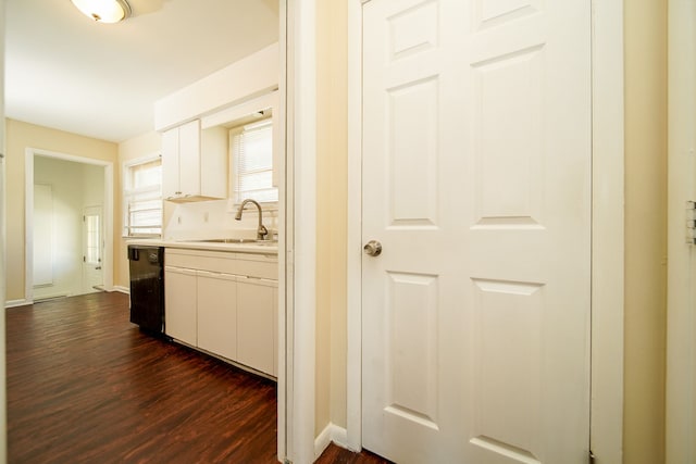 kitchen with a sink, dark wood-type flooring, light countertops, white cabinets, and dishwasher