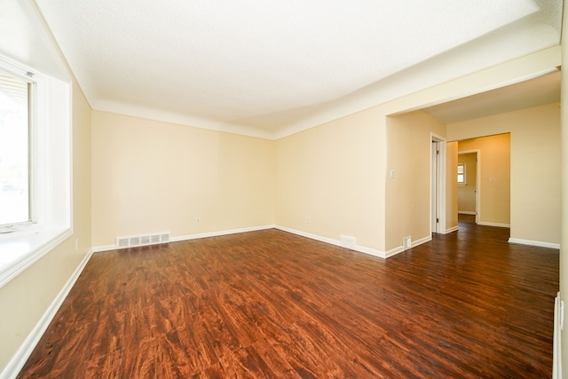 empty room with wood finished floors, plenty of natural light, and baseboards