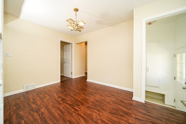 spare room with a chandelier, wood finished floors, and baseboards