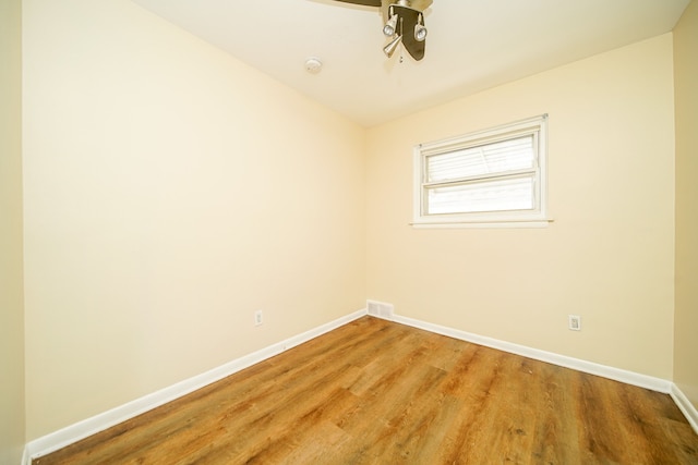 spare room with baseboards, wood finished floors, and a ceiling fan