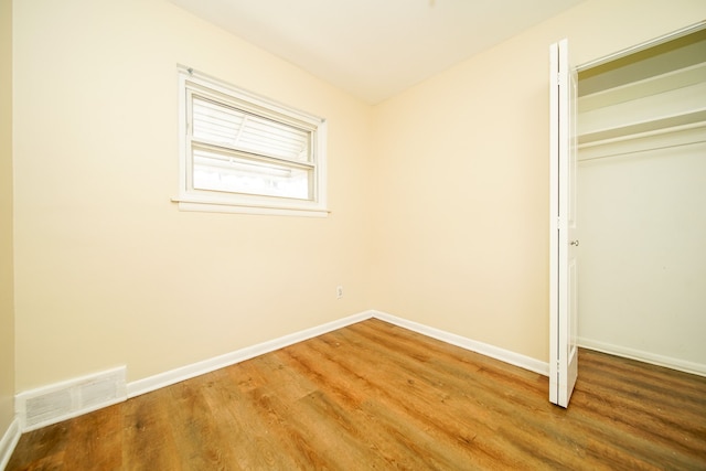 unfurnished bedroom featuring a closet, wood finished floors, and baseboards