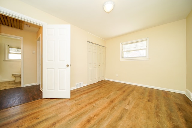 unfurnished bedroom featuring wood finished floors, a closet, and baseboards