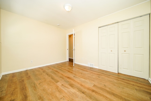 unfurnished bedroom featuring light wood finished floors, baseboards, and a closet