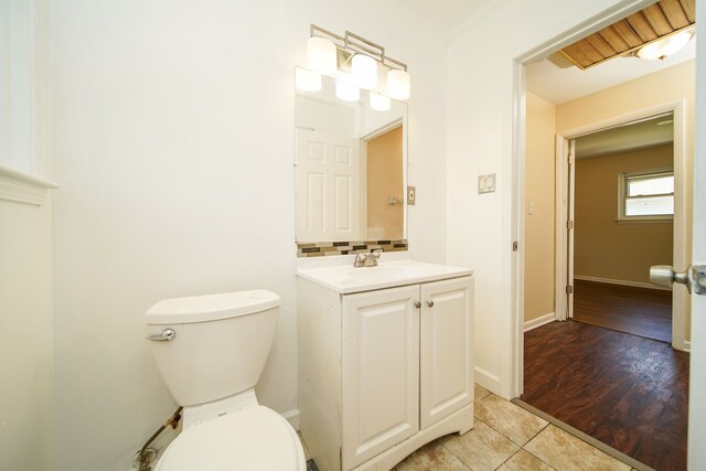half bath featuring toilet, tile patterned flooring, vanity, and baseboards