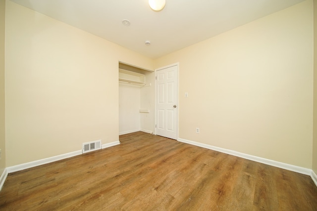 unfurnished bedroom with wood finished floors, baseboards, and a closet