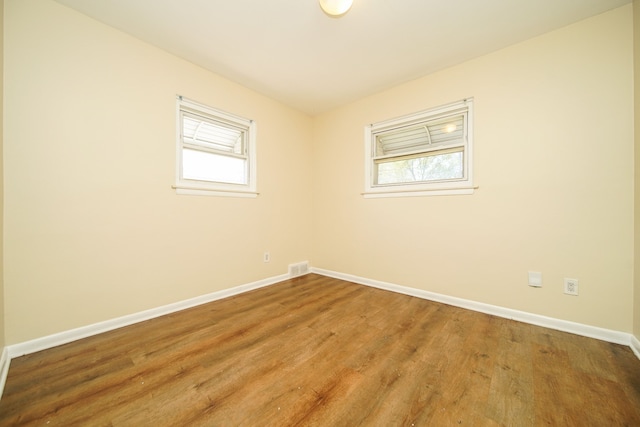 spare room with baseboards and wood finished floors