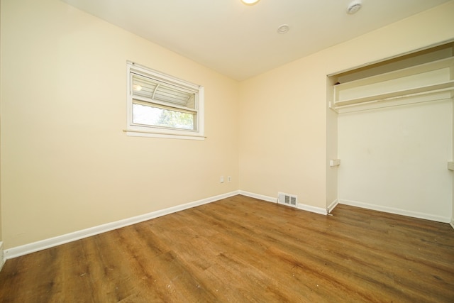 unfurnished bedroom featuring wood finished floors, baseboards, and a closet